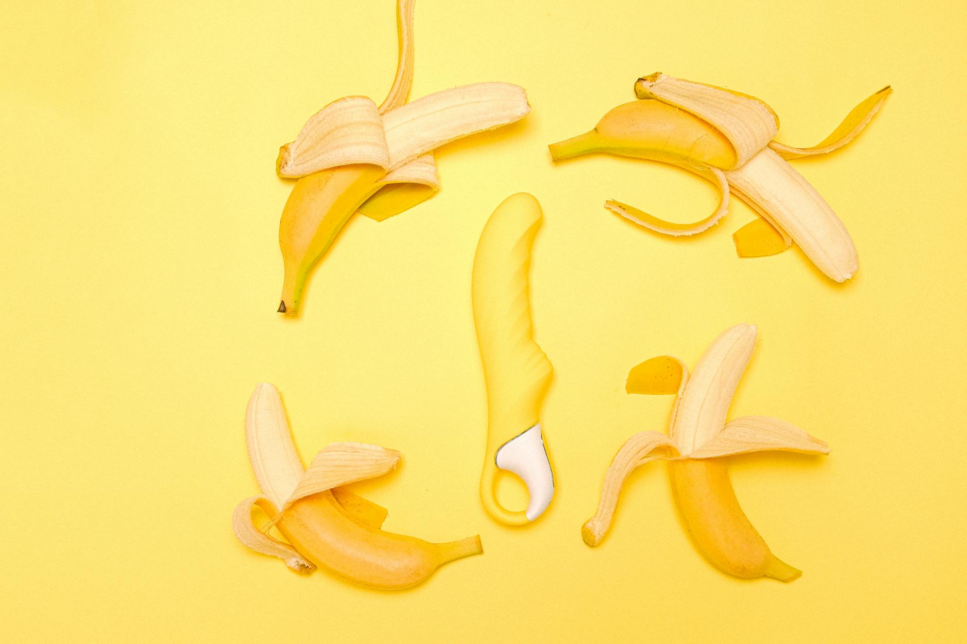 Yellow lemon clitoral vibrator surrounded by fresh citrus on yellow background