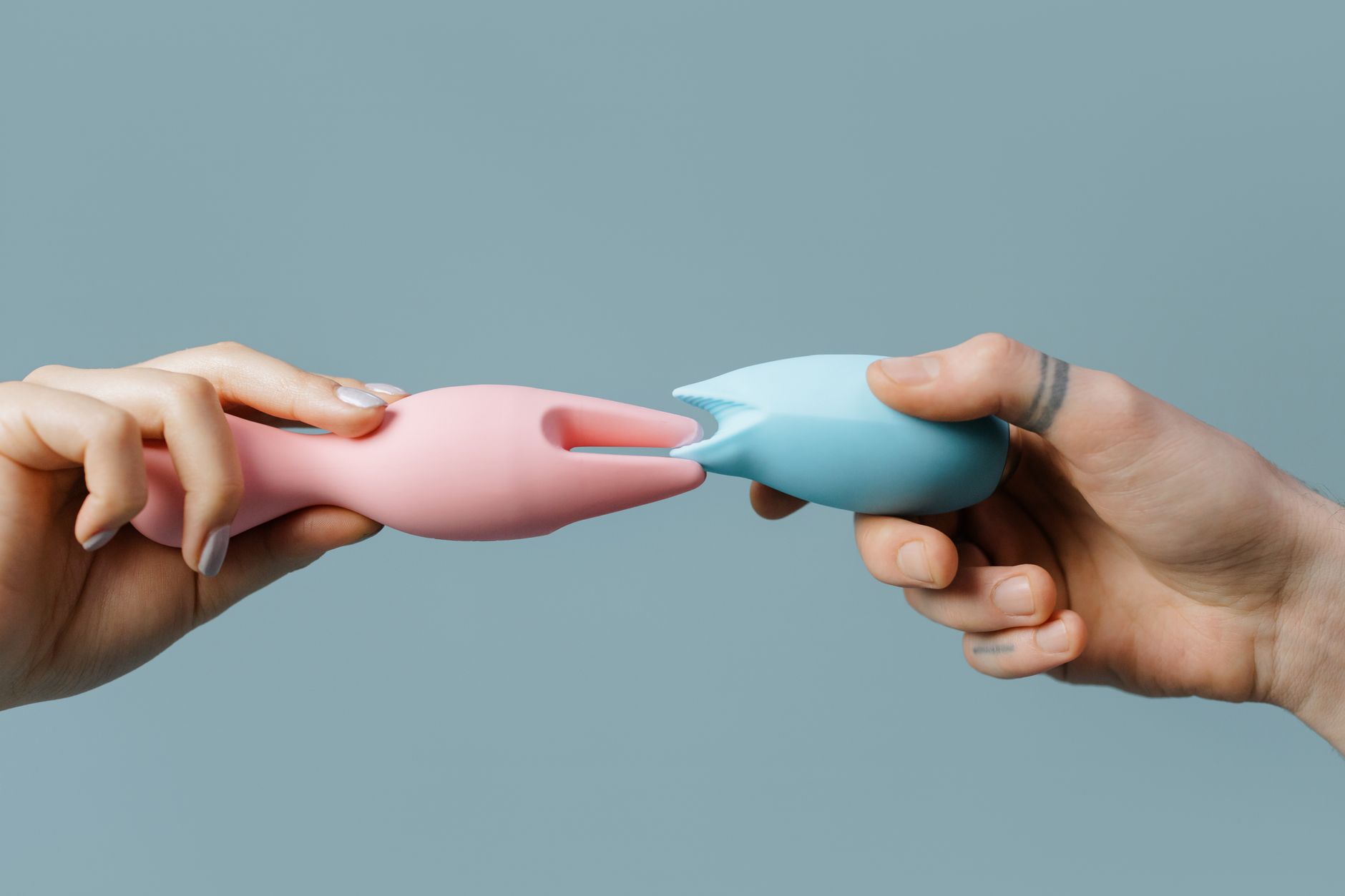 Hands holding colorful silicone toys in various shapes, representing reclamation of pleasure and bodily autonomy.