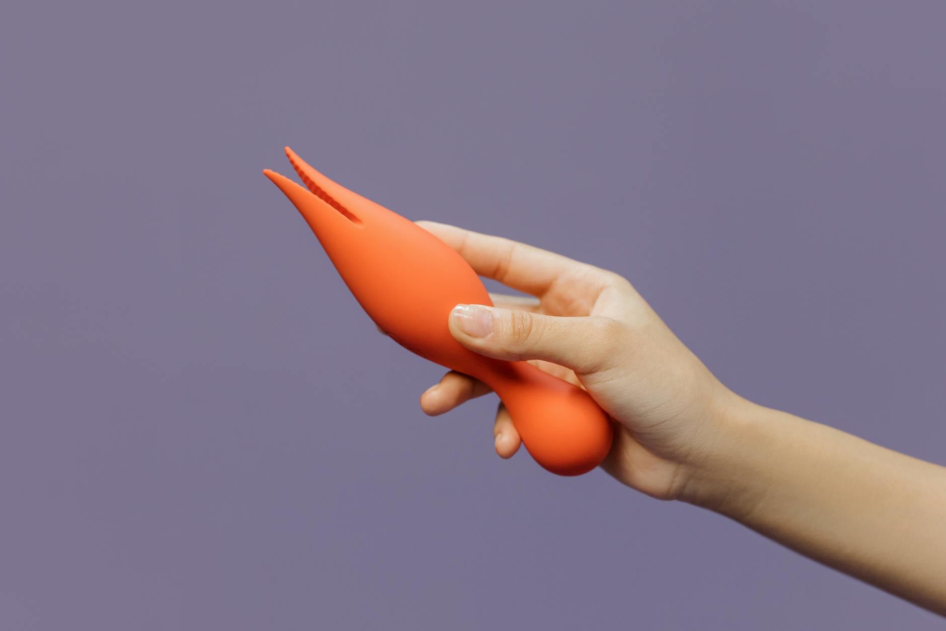A hand holding a lemon vibrator against a purple backdrop, representing modern intimacy and connection