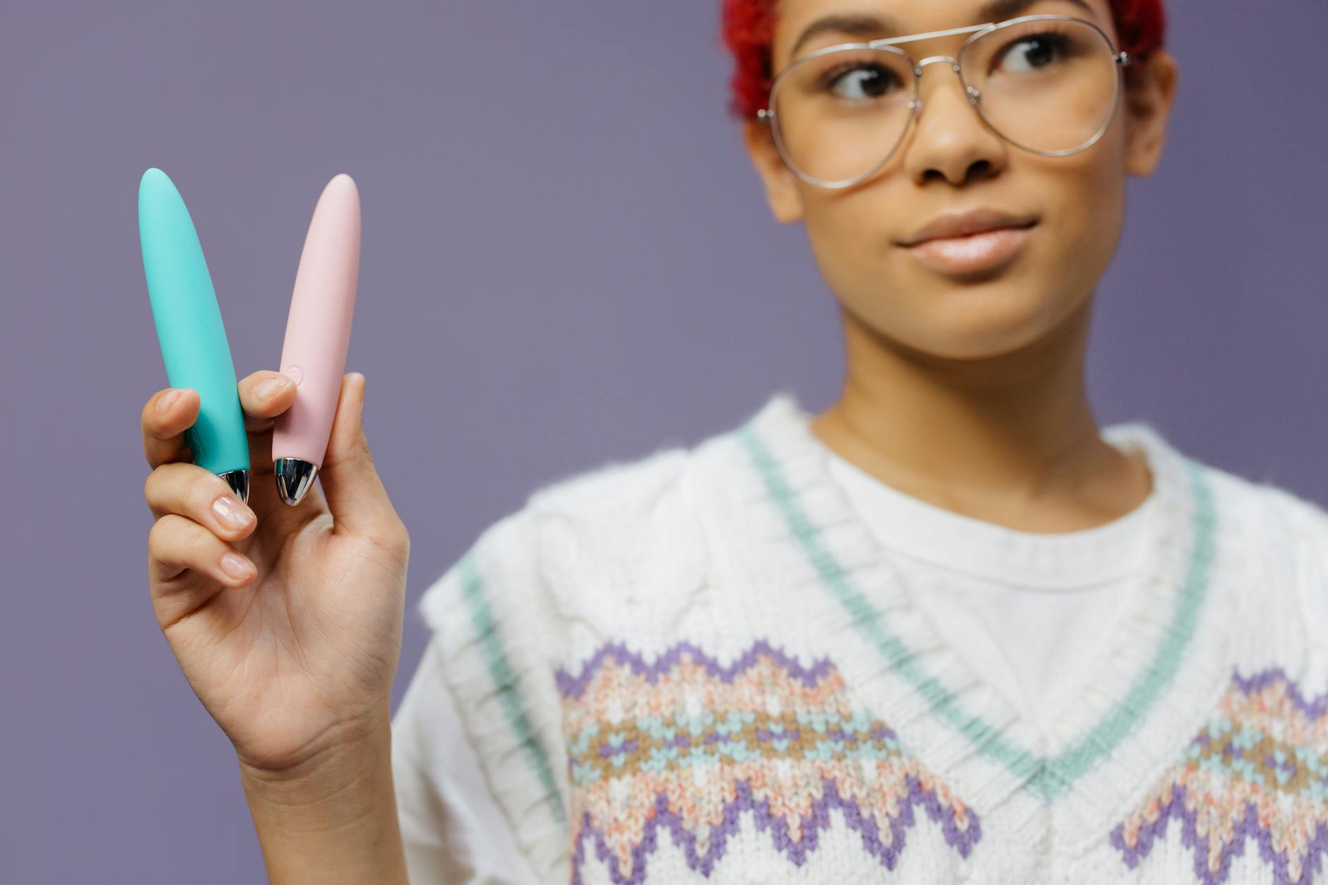 Woman holding colorful lemon vibrators and adult toys against a purple background