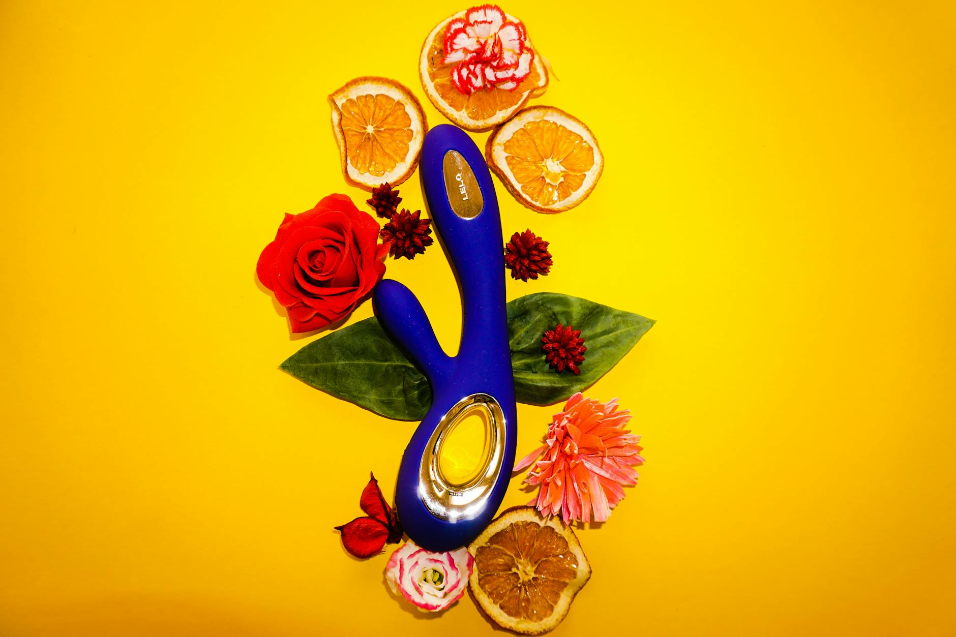 Hands exploring a variety of colorful sex toys arranged on a surface