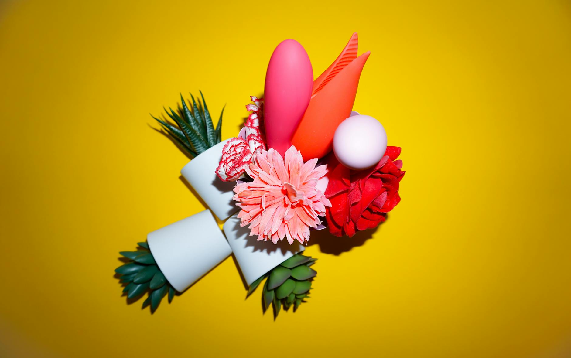 Yellow silicone vibrator surrounded by fresh fruit on a yellow background