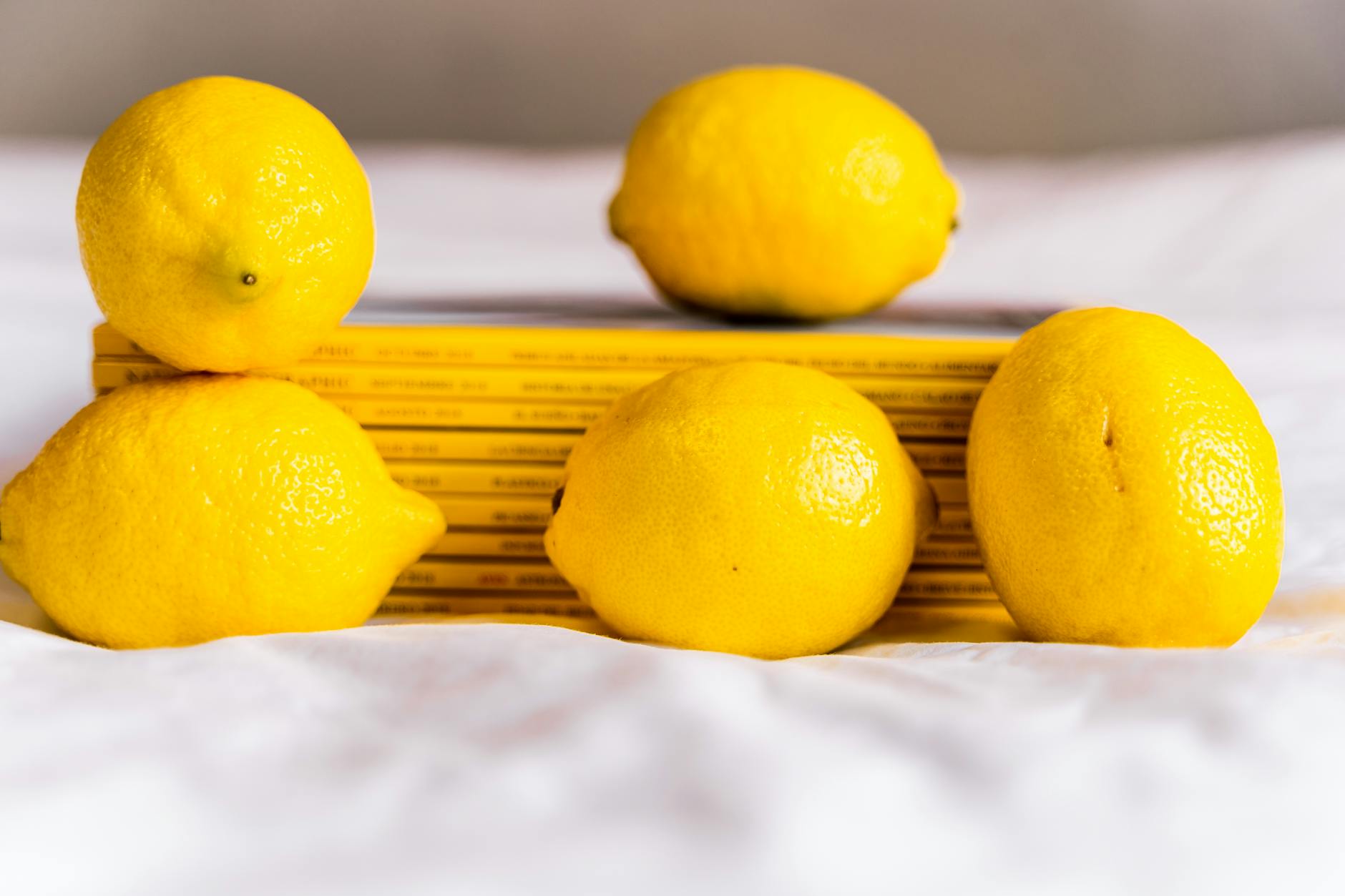 Hand holding a fresh lemon on a soft pink background